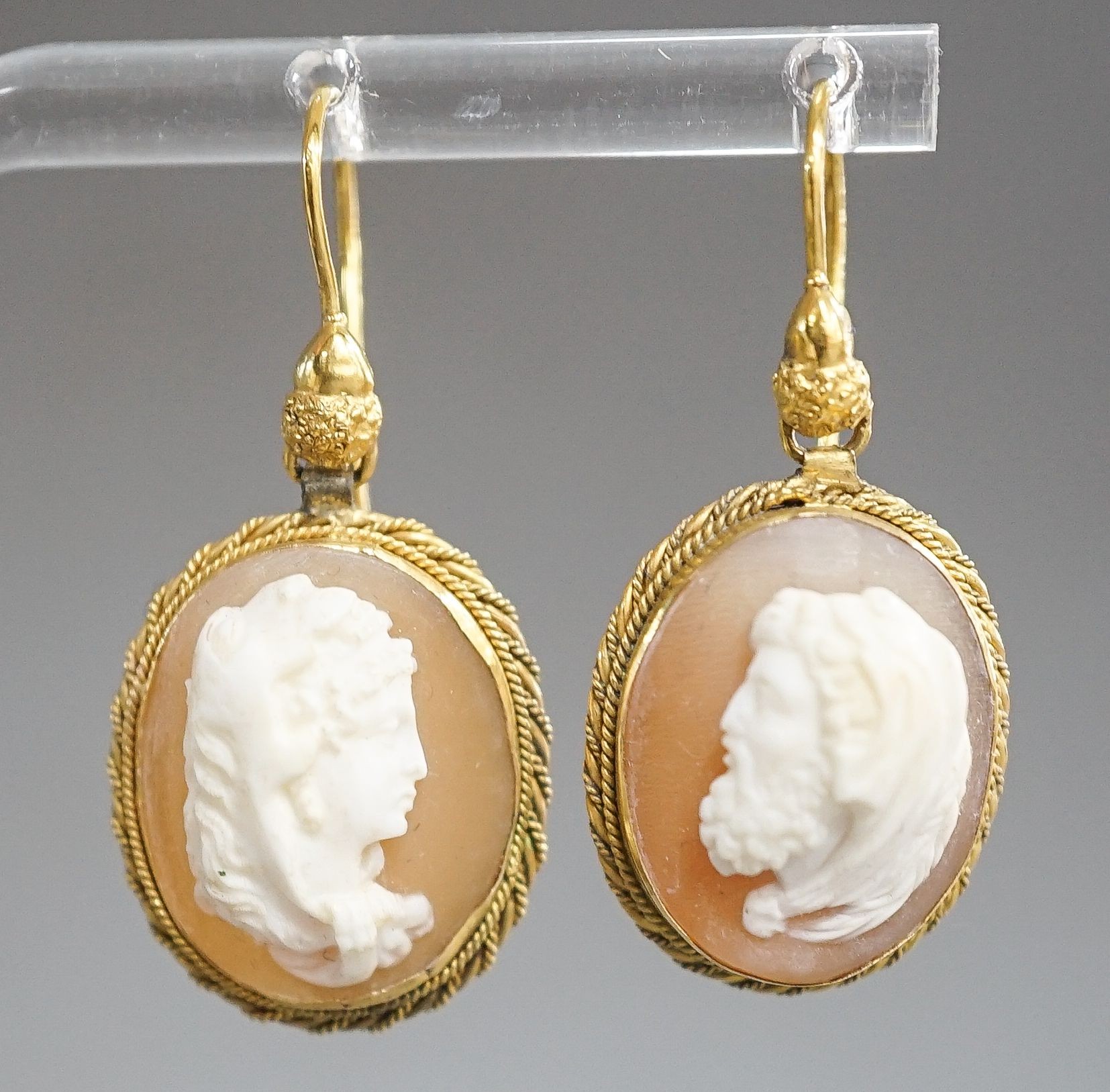 A pair of early 20th century yellow metal and oval cameo shell earrings, carved with a lady to sinister and a gentleman to dexter, overall 40mm, gross 6.2 grams.